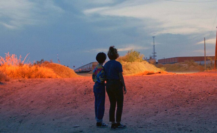 Estefanía “Beba” Contreras (left) and Silvia Del Carmen Castaños (right) watch a train in the distance near the U.S.-Mexico border at dusk in a scene "from Hummingbirds."