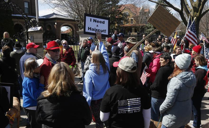 Protesters gather outside Minnesota Gov. Tim Walz's official residence in St. Paul on Friday, calling for him to loosen stay-at-home restrictions imposed because of the coronavirus.