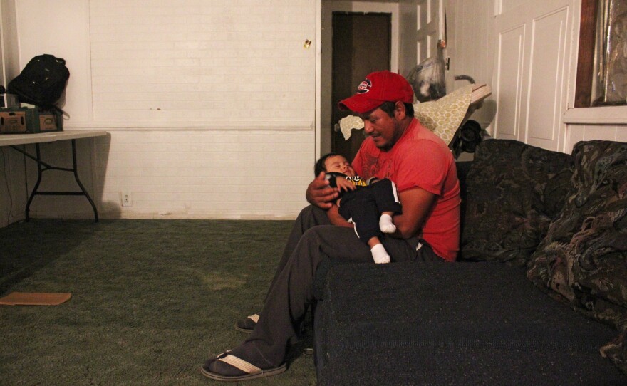 Nabor Segundo, with his infant, son, Alan. He and his family share this two-bedroom trailer with one other family.