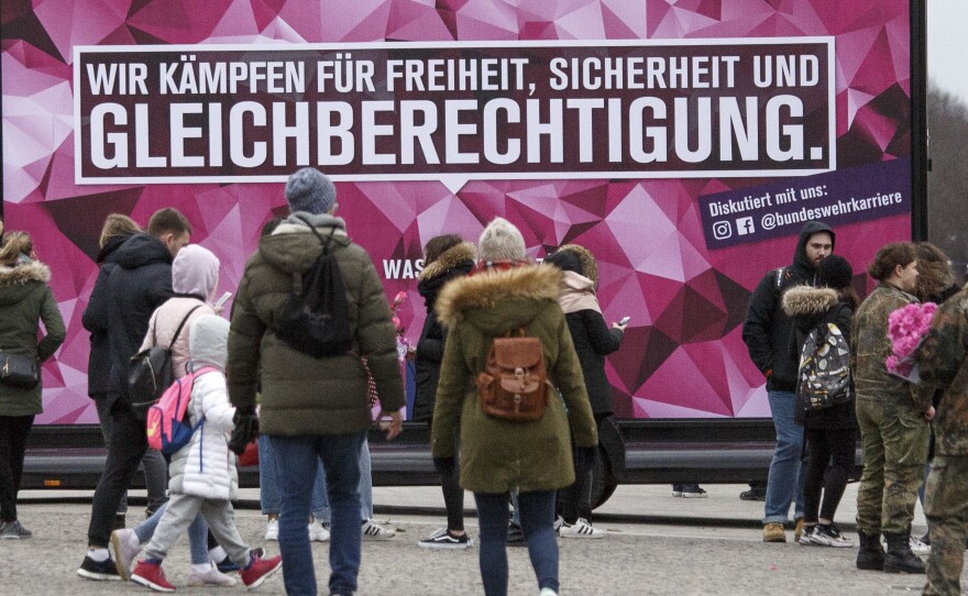People pass a banner that reads: "We fight for freedom, security and equal rights" in front of the  Brandenburg Gate on Friday in Berlin.