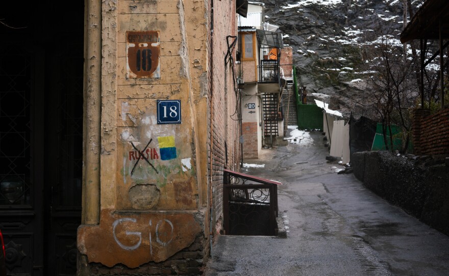 Graffiti on a street corner in downtown Tbilisi, Georgia, shows Russia crossed out and the flag of Ukraine next to it.