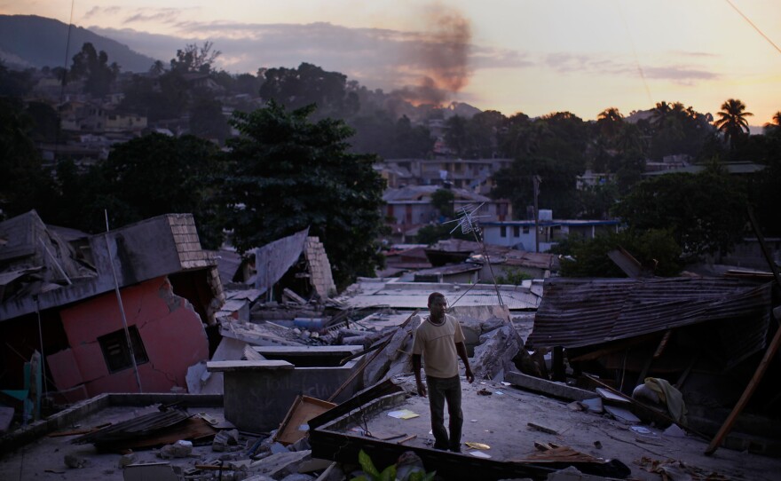 After the quake of 2010, a man stands on a rooftop yelling out for any sign of his missing relatives in a Port au Prince neighborhood.
