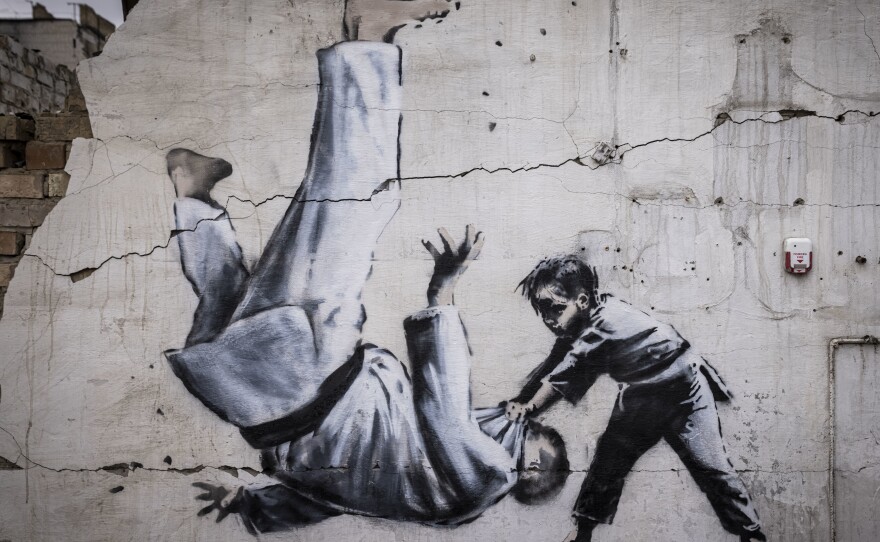 Graffiti of a child throwing a man on the floor in judo clothing is seen on a wall amid damaged buildings in Borodyanka on Friday.