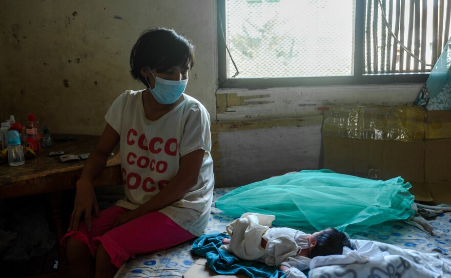 Jessa Tayombong sits with her baby, Josie. Even though home births are illegal in the Philippines, Tayombong delivered the child at home.