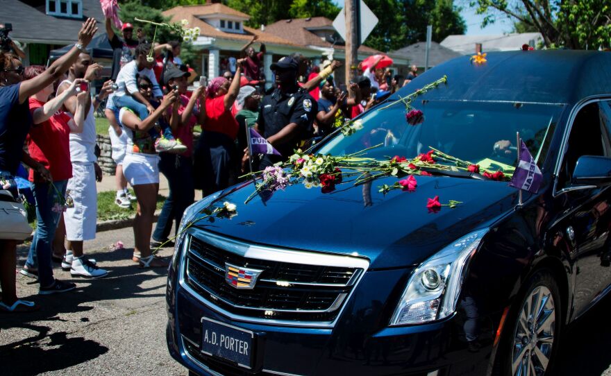 The hearse carrying boxing legend Muhammad Ali drives past his childhood home where mourners throw flowers as they pay their respects in Louisville, Ky.