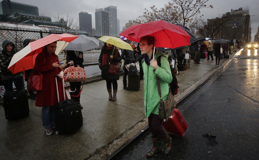 Passengers wait for a BoltBus to arrive during a light rain, Wednesday, Nov. 27 in New York. A wall of storms packing ice, sleet and rain could upend holiday travel plans as millions of Americans take to the roads, skies and rails for Thanksgiving.