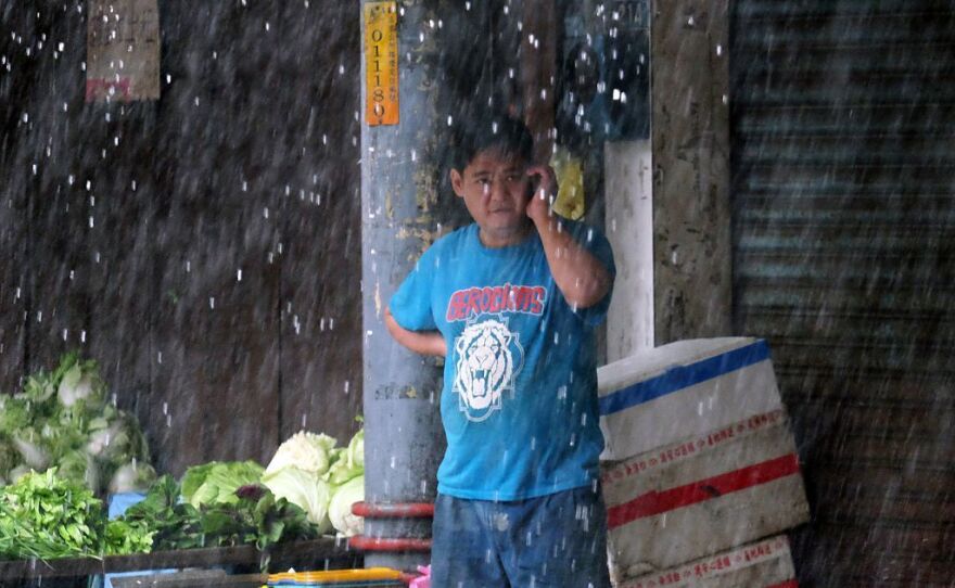 A vegetable vendor speaks on the cellphone at a market in Xindian district of New Taipei City, as Typhoon Megi approached Taiwan on Tuesday.