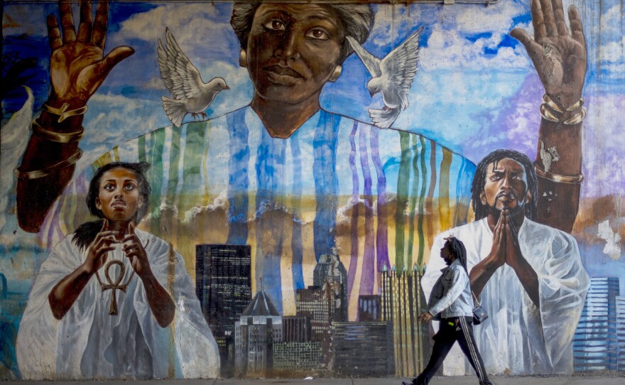 Sheridan Newsome, 21, walks by a mural in Pittsburgh's Homewood neighborhood. Despite receiving the consistent support of Black communities, many voters here say Democratic leaders have largely failed to effectively address enduring problems like police violence, discrimination and income inequality that have disproportionately hurt Black residents in Pittsburgh.