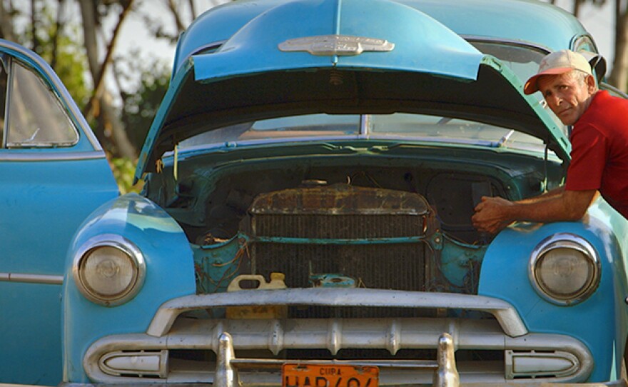 Cuba native with the classic car hood up.