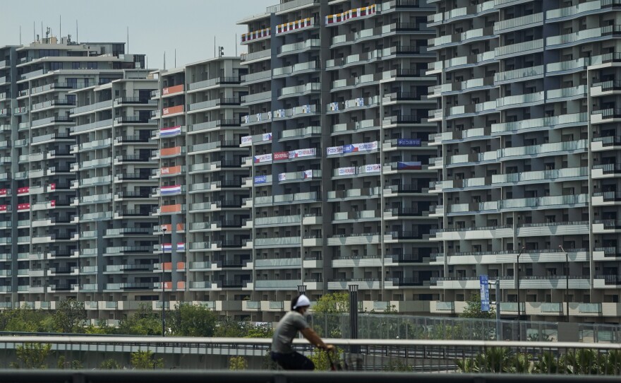 A man rides a bike near the village for the Summer Olympics in Tokyo. On Saturday, officials announced the first case of COVID-19 found at the center housing thousands of athletes.