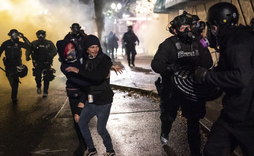 Protesters look for an escape while Portland police disperse a crowd in Portland, Ore. Wednesday. Violent protests erupted following the results of a grand jury investigation into the police shooting death of Breonna Taylor.