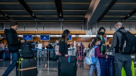 Travelers, some wearing masks, wait in long lines to check luggage before going through airport security on their way out of San Diego, Calif. Dec. 23, 2022.