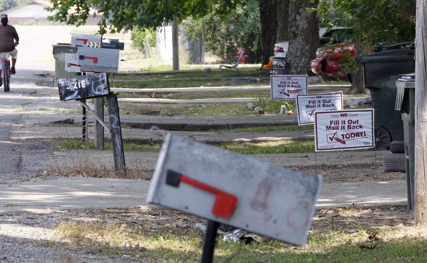 A bicyclist pedals past signs promoting the 2010 census outside homes in Rolling Fork, Miss., in 2010.
