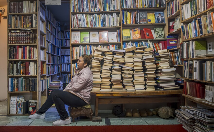 Citlali Márquez Solórzano sits among the stacks of books in the bookstore she operates with her father, Miguel Márquez San Juan. The store, Libros, Café y Jazz, celebrates 15 years of offering used books to Tijuana residents, Oct. 18, 2024.