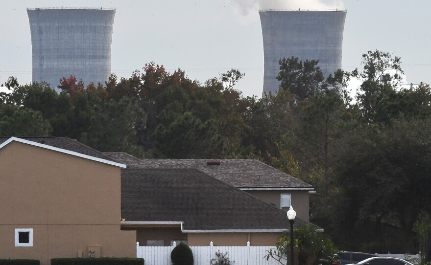 The cooling towers at the Stanton Energy Center, a coal-fired power plant, are seen behind a home in Orlando.