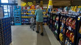 Pictured, a man walking out of a grocery store pushing a shopping cart on July 30, 2025. 