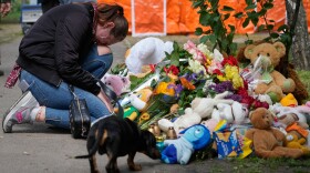 A woman cries as she lays down flowers in front of a house heavily damaged after a Russian strike on residential neighbourhood in Kyiv, Ukraine, on Friday, May 15, 2026.