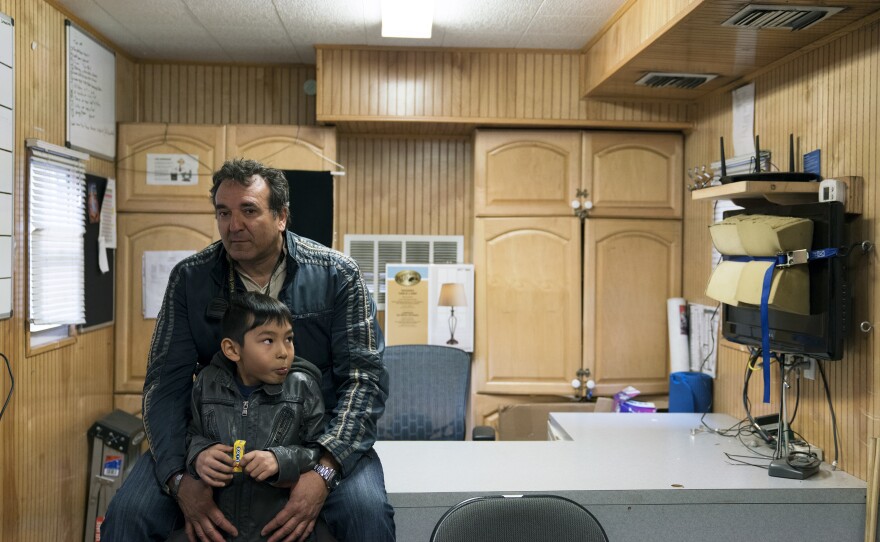 Peter Gold holds his son while sitting on his desk in the mobile administration offices. Gold used to be a trapeze performer in the circus and is now the assistant general manager. His son, Jerry, is an understudy for a young clown.