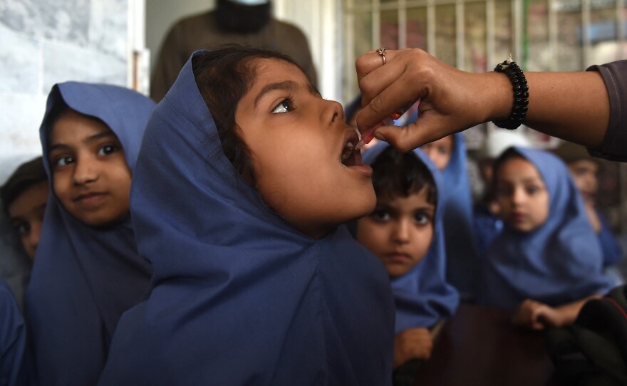A health worker administers the oral polio vaccine to a young girl as other children wait for their turn at a school in Karachi, Pakistan on February 28, 2022. In response to an uptick in cases of vaccine-derived polio — a form of the disease that stems from the oral vaccine — many countries are rolling out a new oral polio vaccine.