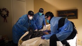 Emergency medical workers Jacob Magoon, from left, Joshua Hammond and Thomas Hoang lift a patient onto a gurney in Placentia, Calif., Saturday, Jan. 9, 2021.