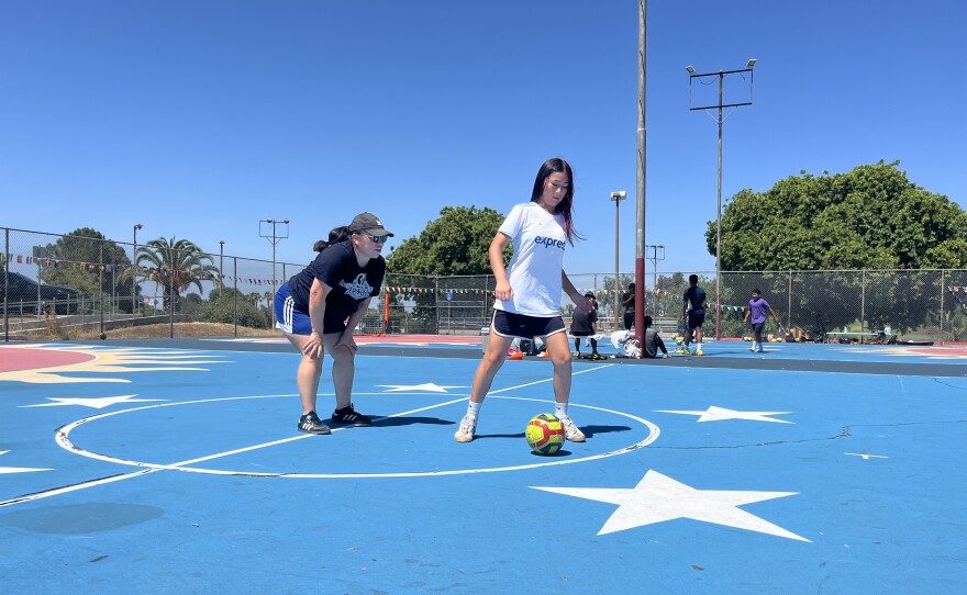 Ana Diaz coaches coaches a young soccer player at the basketball courts in San Diego's Colina Del Sol Park on July 10, 2025.