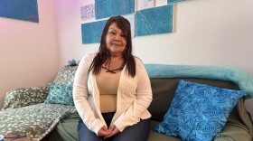 Isabelle Fuentes sitting in her one-bedroom apartment at Jacaranda on Ninth, an affordable housing complex in Cortez Hill downtown San Diego, May 7, 2026.