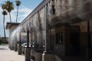 A person weaves through mist at the bus station in El Centro, one of two specially designated cooling zones during the extreme heat wave on July 16, 2024.