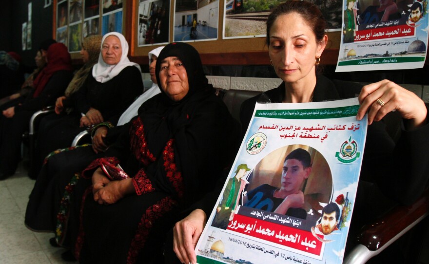 The mother (right) of Abdel Hamid Abu Srour (portrait) mourns with family members as she receives condolences at the Al-Ruwad Center in the Aida Refugee Camp near Bethlehem on Friday.