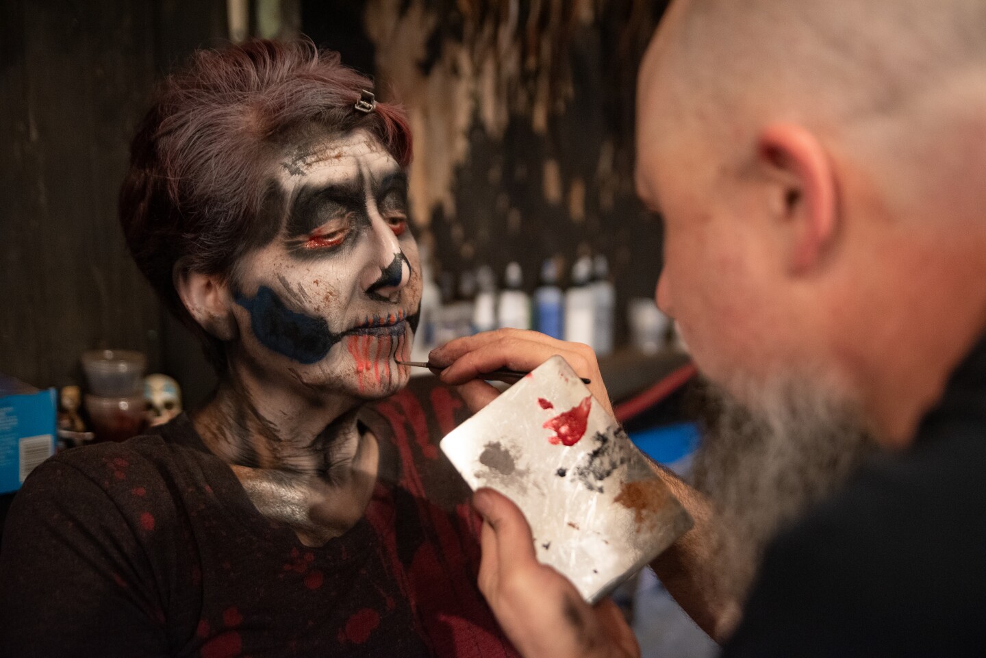 KPBS arts reporter Beth Accomando gets some detail work on her makeup from Stuart Hirsch before heading out to the graveyard to be a scare actor for one night at The Haunted Trail in Balboa Park on Sept. 25, 2025.