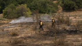Two firefighters work to contain the Monte Fire near Lakeside, California on June 18, 2025.