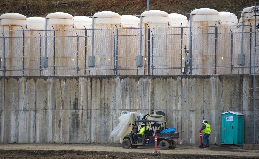 Once it is safe to remove the spent fuel from the pool, it's stored outside in white, metal casks. They are lined up on a concrete base behind razor wire, against a hillside near the power plant.