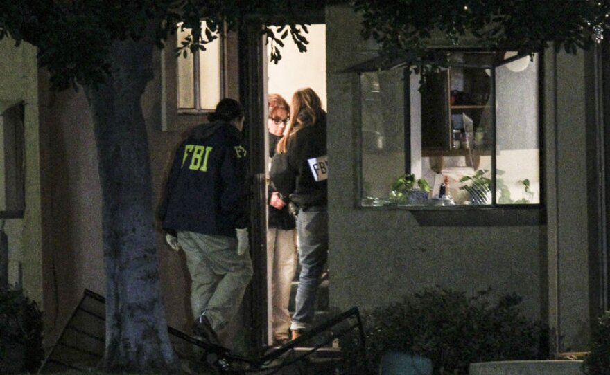 FBI agents search outside a home in connection to the shootings in San Bernardino, Thursday, in Redlands, Calif.