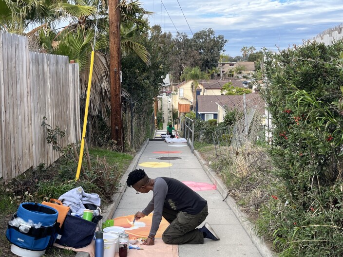 Shannon White paints a poppy on the walkway leading to Valencia Park's secret stairs, Jan. 13, 2022.
