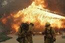 Three firefighters brace themselves from explosive heat coming from a burning home in the Rancho Bernardo area of San Diego, set off by a wildfire seen here in a file photo taken Monday, Oct. 22, 2007. 