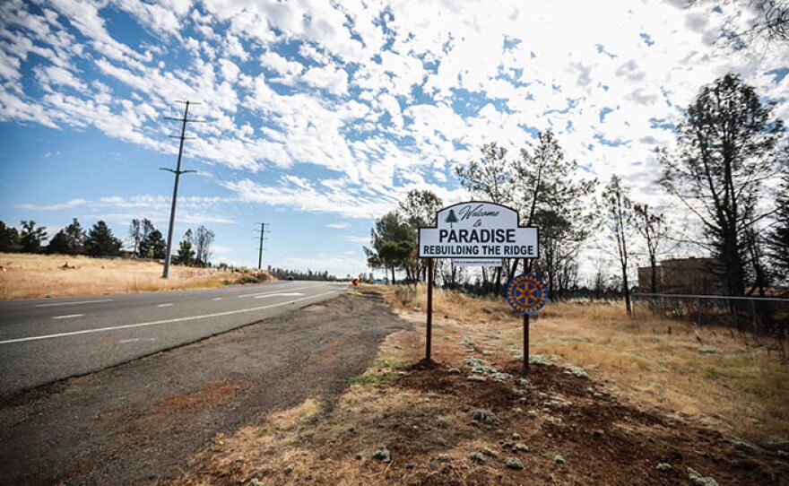 A sign on the side of the road reads "Welcome to Paradise - Rebuilding The Ridge."