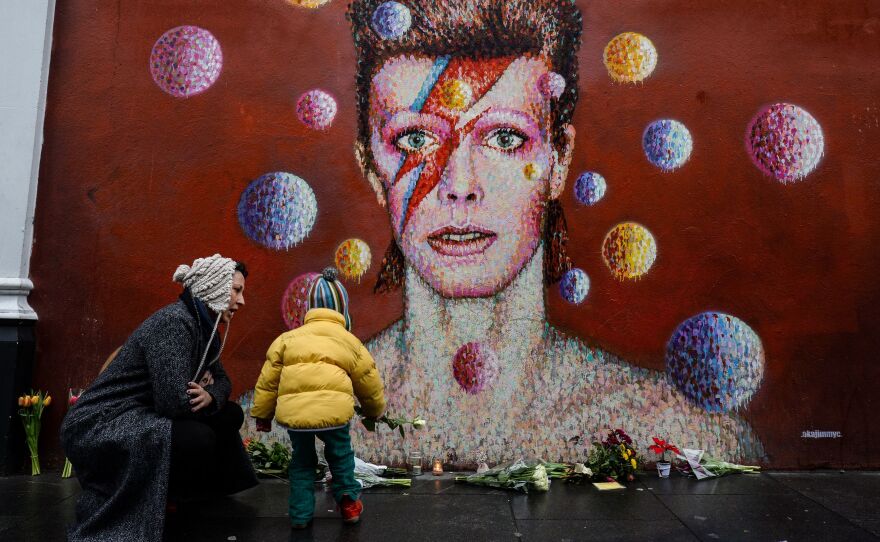 Flowers and other mementos piled up beneath a mural of David Bowie painted by Australian street artist James Cochran, aka Jimmy C, in Brixton, South London.