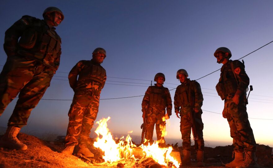 Iraqi Kurdish Peshmerga fighters stand next to a fire as they gather on the top of Mount Zardak, about 25 kilometres east of Mosul, on Monday.