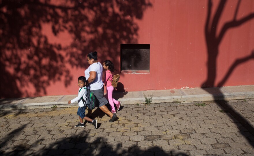 A woman walks two children in Jocotenango.