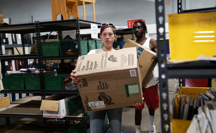 Melissa Badeker and a Maryland Book Bank staff member carry donations through the warehouse.