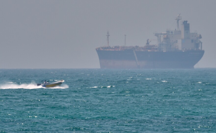 A boat sails past a tanker anchored on the Strait of Hormuz off the coast Qeshm island, Iran, April 18, 2026.