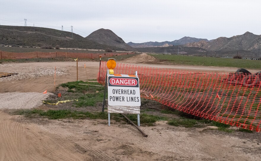 The JVR Energy Park construction site is outlined by orange fencing and framed by powerlines above. Photo taken on Jan. 21, 2026.