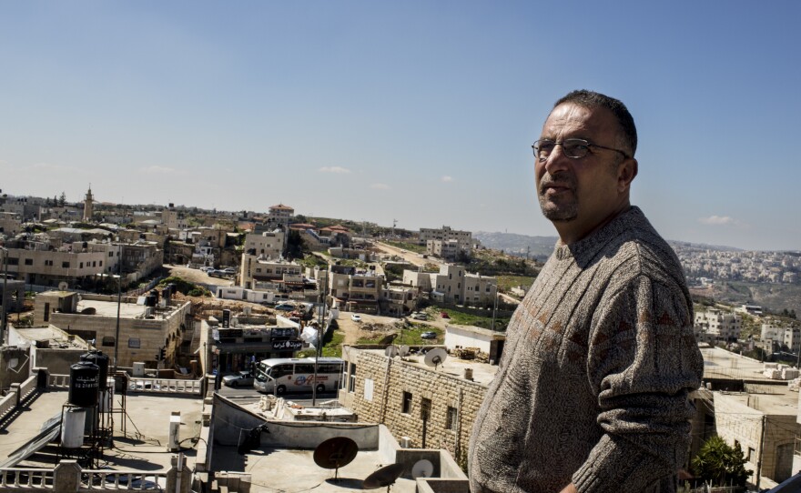 Palistinian Walid abu Khudair stands on his rooftop, which is directly across the street from the light rail station and the spot where his cousin, 16, was kidnapped and later murdered last summer.