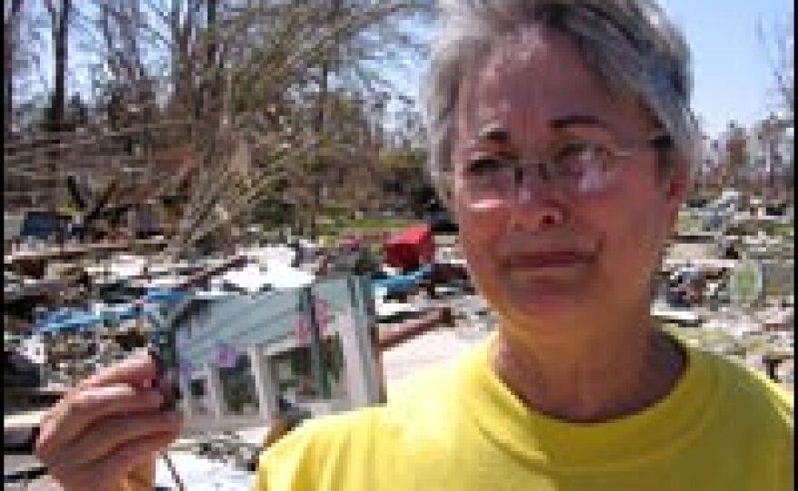 Kathy Pinn holds a photo of her Waveland, Miss., store while standing in front of the wreckage where it used to be.