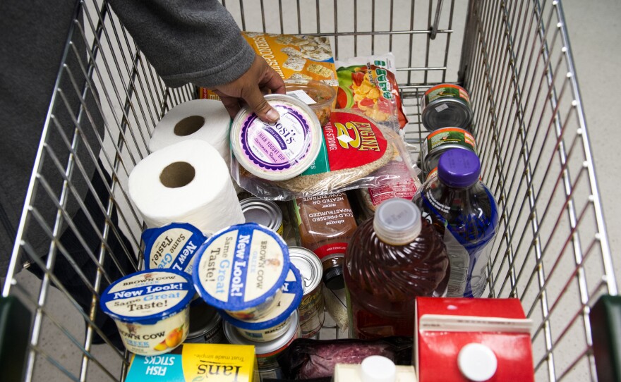 A food pantry client adds a carton of yogurt to her cart at the food pantry at Jewish Family Services in Denver, Colo.