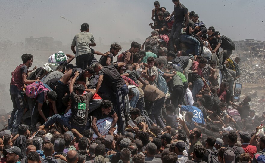 Palestinians climb onto an aid truck as it enters the Gaza Strip via the Zikim Crossing. They're hoping to obtain flour during what the Israeli military called a "tactical suspension" in operations to allow humanitarian aid through. Gaza. July 27, 2025.