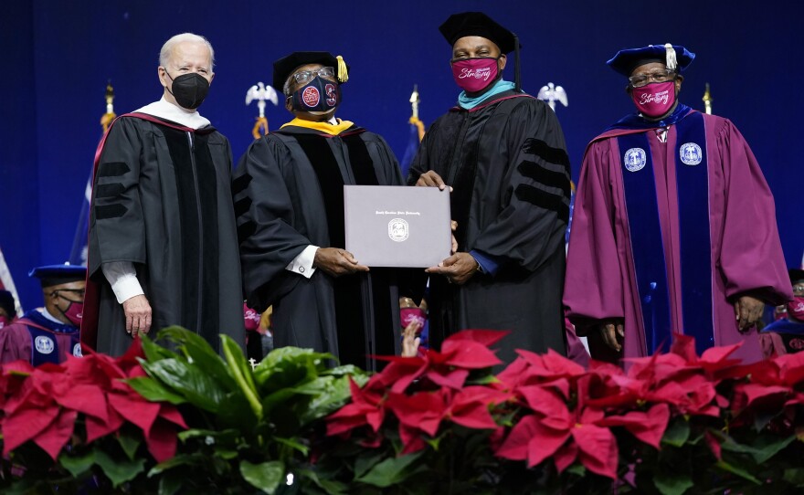 Rep. Jim Clyburn, D-S.C., second from left, holds his history degree with South Carolina State University Interim President Alexander Conyers, second from right, on stage with President Joe Biden, left, and Rodney Jenkins, Chairman of the Board of Trustees, right, during the South Carolina State University's 2021 Fall Commencement Ceremony in Orangeburg, S.C., Friday, Dec. 17, 2021.