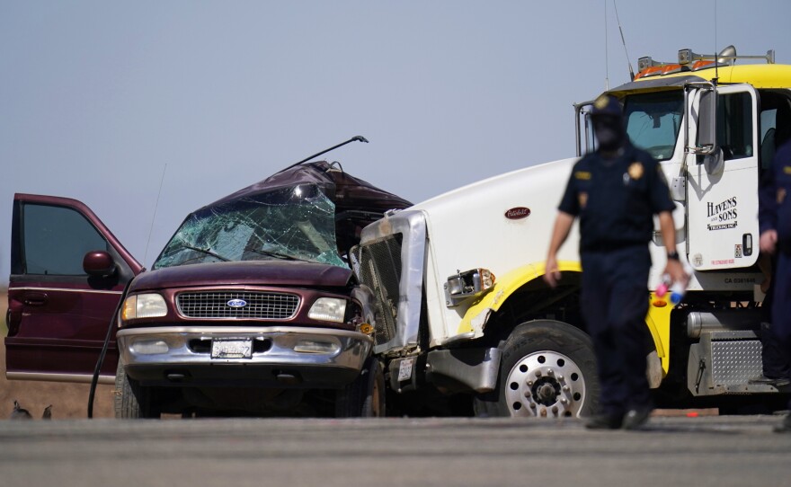 Law enforcement officers work at the scene of a deadly crash near Holtville, Calif., on Tuesday. Authorities say a truck crashed into an SUV carrying 25 people on a Southern California highway, killing at least 13 people.