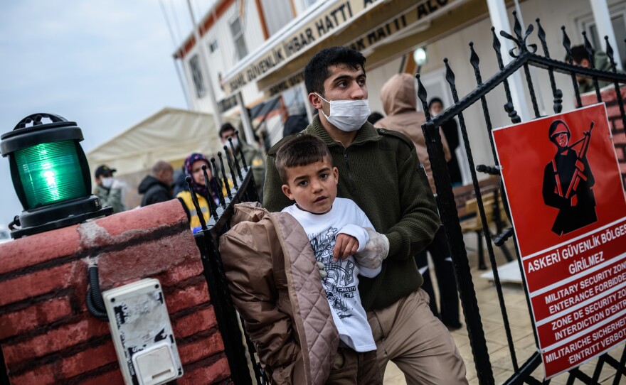 A Turkish coastguard escorts a rescued child migrant after a boat sank while trying to cross from Turkey to Greece. The migrants, from Syria, Myanmar and Afghanistan, set sail from the Canakkale province to reach the nearby Greek island of Lesbos.