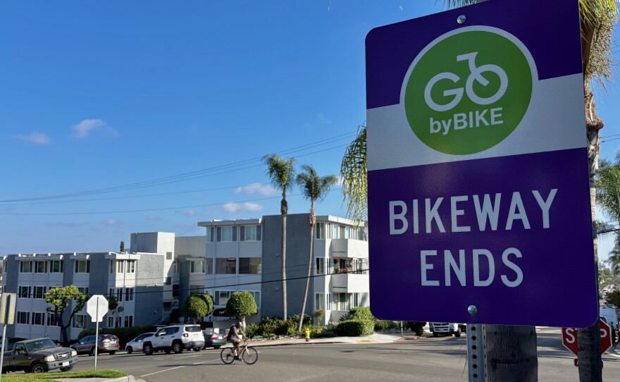 A sign reads "Go by bike — bikeway ends" as a cyclist rides past on Robinson Avenue, Sept. 17, 2026.