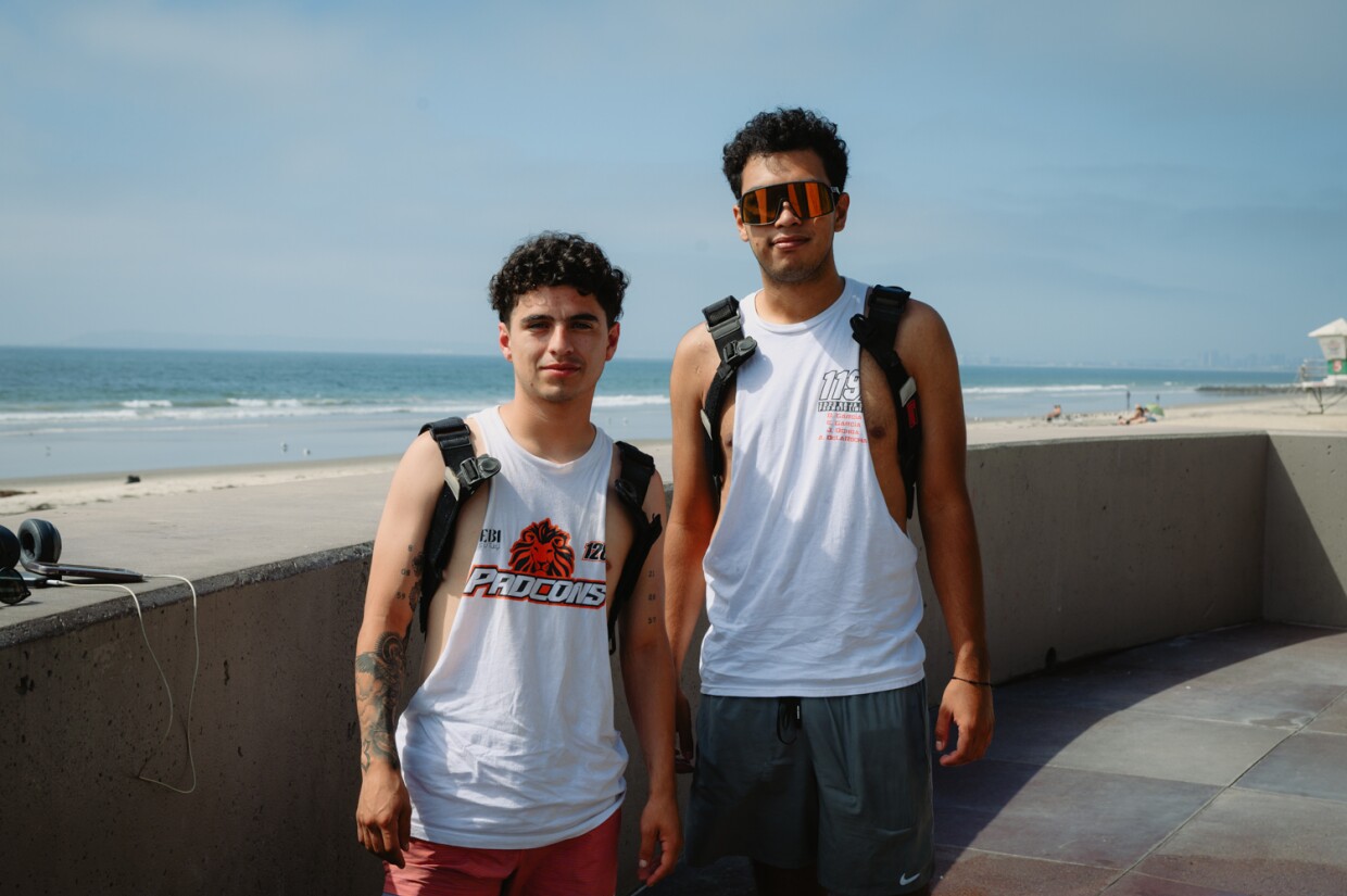 Alberto, left, 20, and Ezra, 21, stand for a portrait at the showers next to the IB Pier in Imperial Beach after a long run from Chula Vista on September 3, 2024.